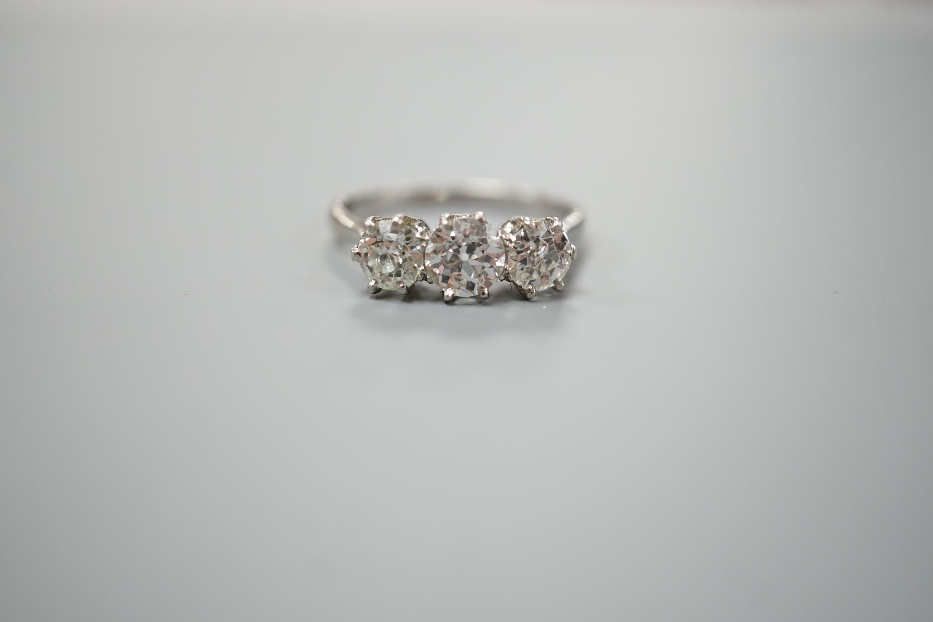 A white metal (stamped Plat) and three stone diamond set ring, size P/Q, gross weight 3.7 grams